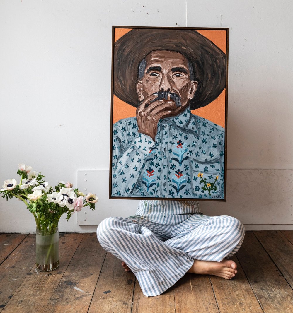 Sammy Veall holding a portrait painting up in front of her