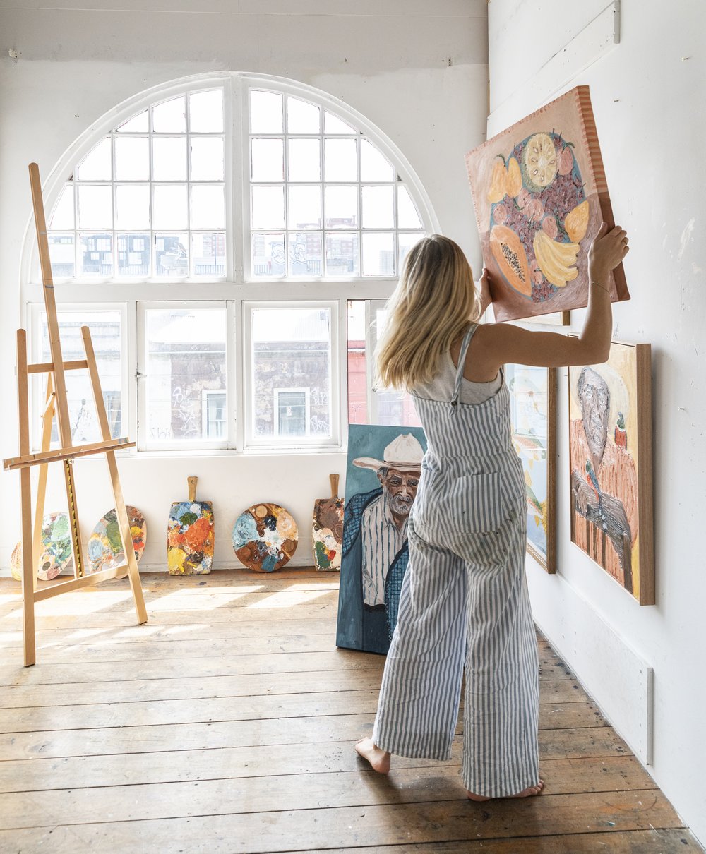 Artist Sammy Veall in her studio carrying on of her paintings