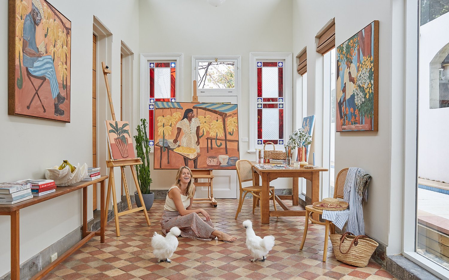 Artist Sammy Veall Sitting on the floor in her studio with chickens 