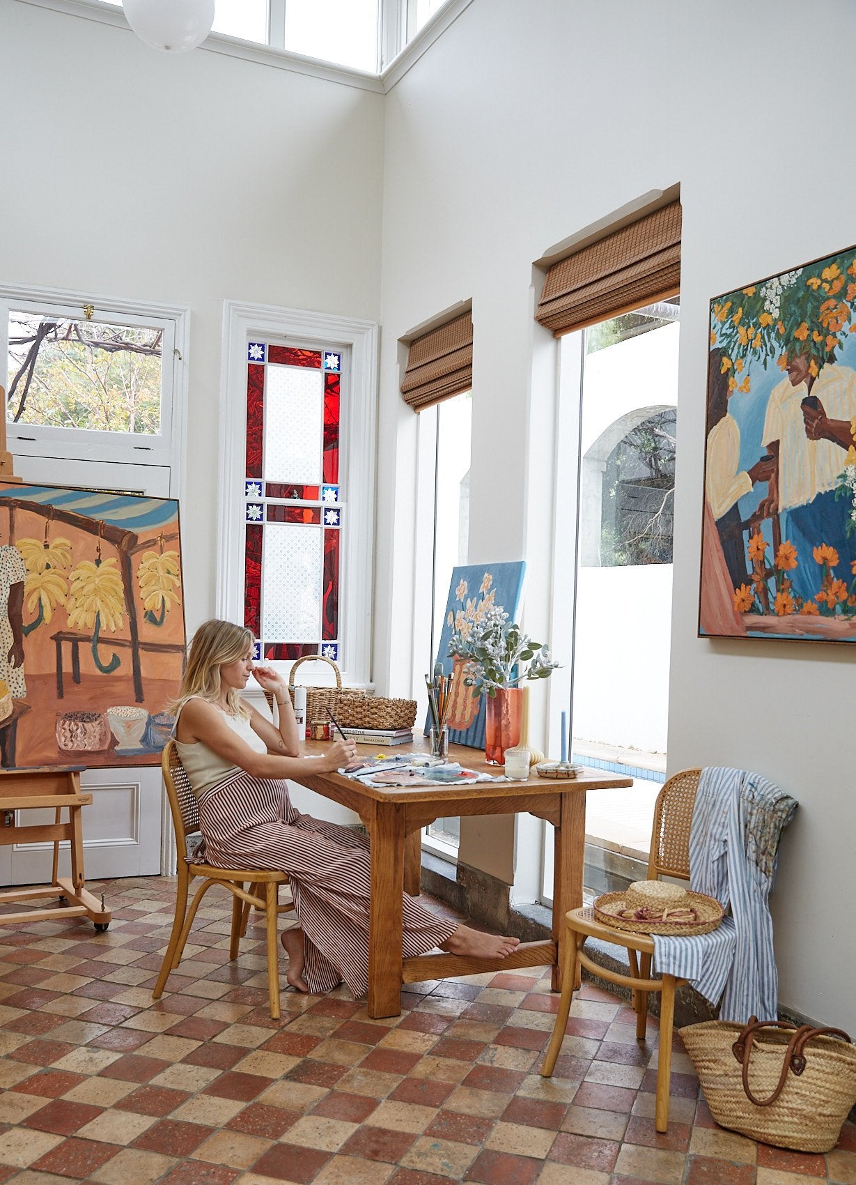 Artist Sammy Veall sittting in her studio working surrounded by her art